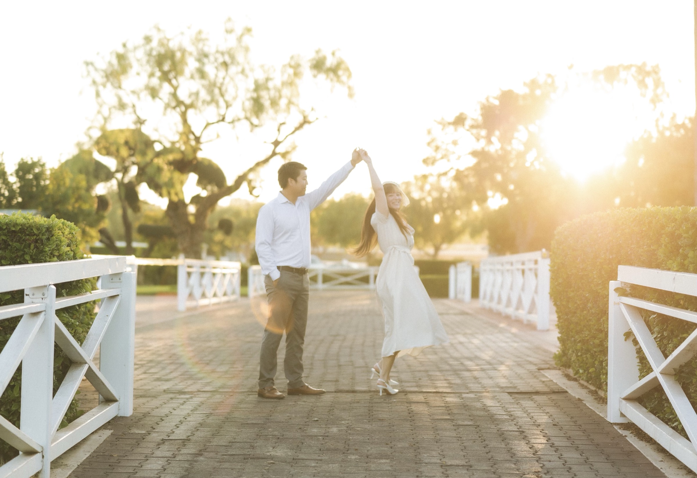 Joshua and Marina dancing at golden hour along the white rails of Santa Anita Park